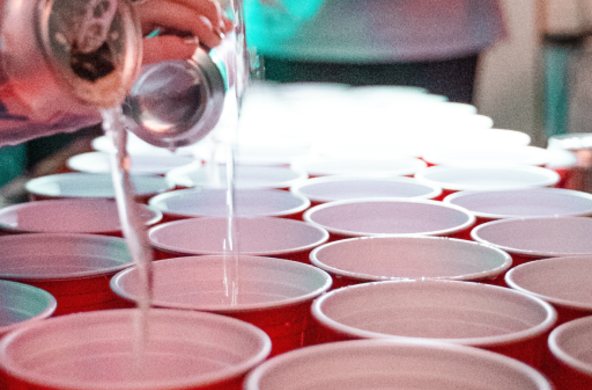 Stock photo of red cups and someone pouring alcohol into them.
