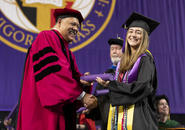 President Rougeau presents a diploma to a student at commencement 2024