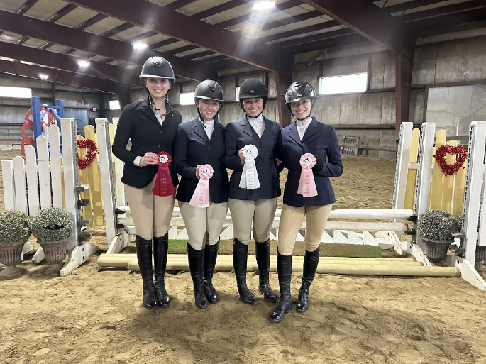 Equestrian team at a competition with their winning ribbons