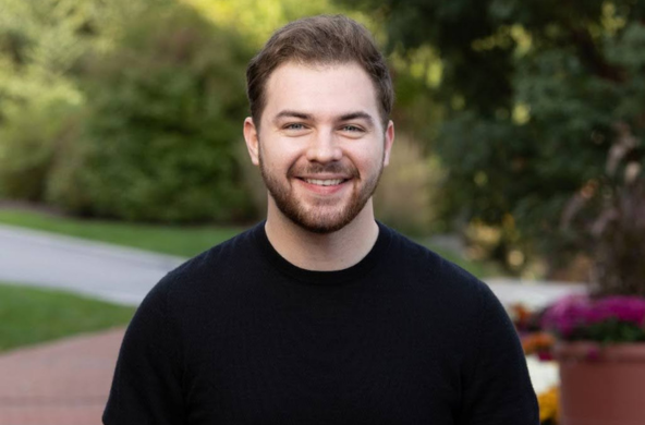 a young man in a dark sweater smiling at the camera