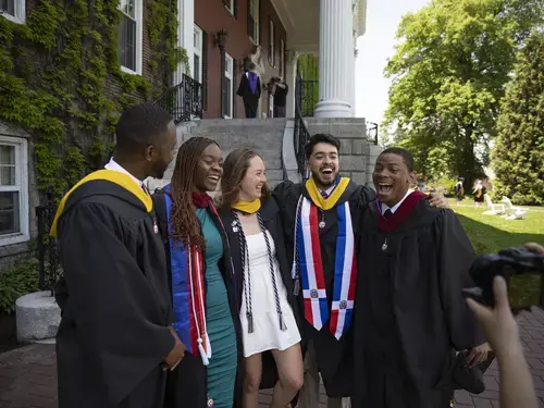 Four graduates laughing at commencement