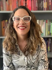 woman in glasses in front of a full bookcase