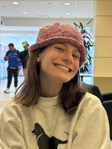 a young woman in a pink hat and grey sweatshirt