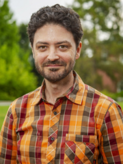 man in an orange flannel shirt smiling at the camera