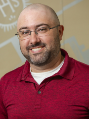 man in a red polo shirt smiling at the camera