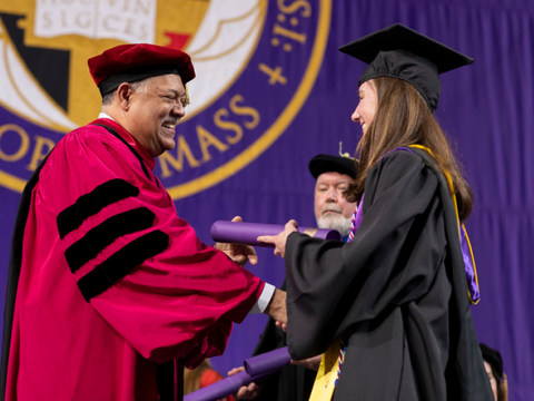 President Vince Rougeau handing a graduate her diploma