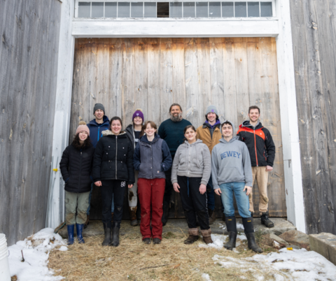 young adults standing in front of a barn